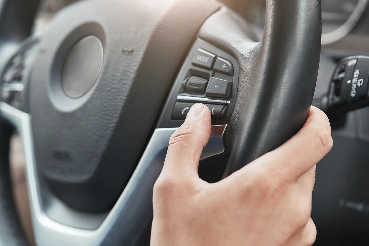 drivers thumb pressing controls on cars steering wheel