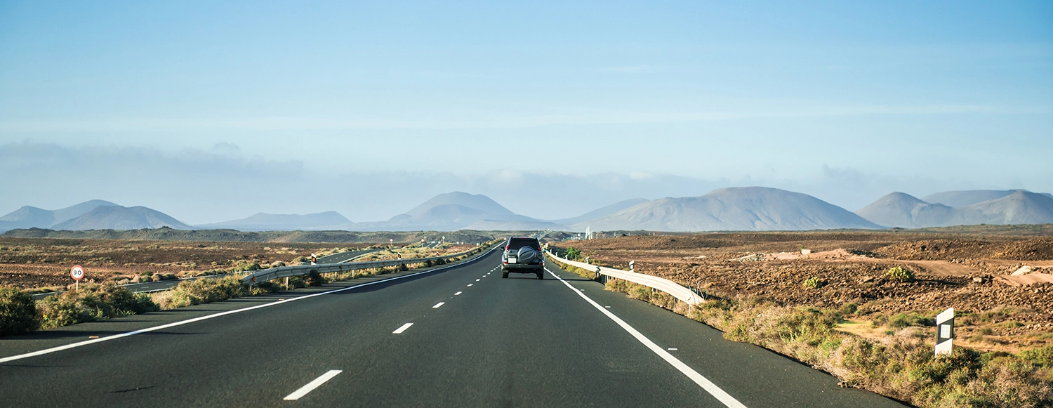 road disappearing into the horizon line into a blue sky