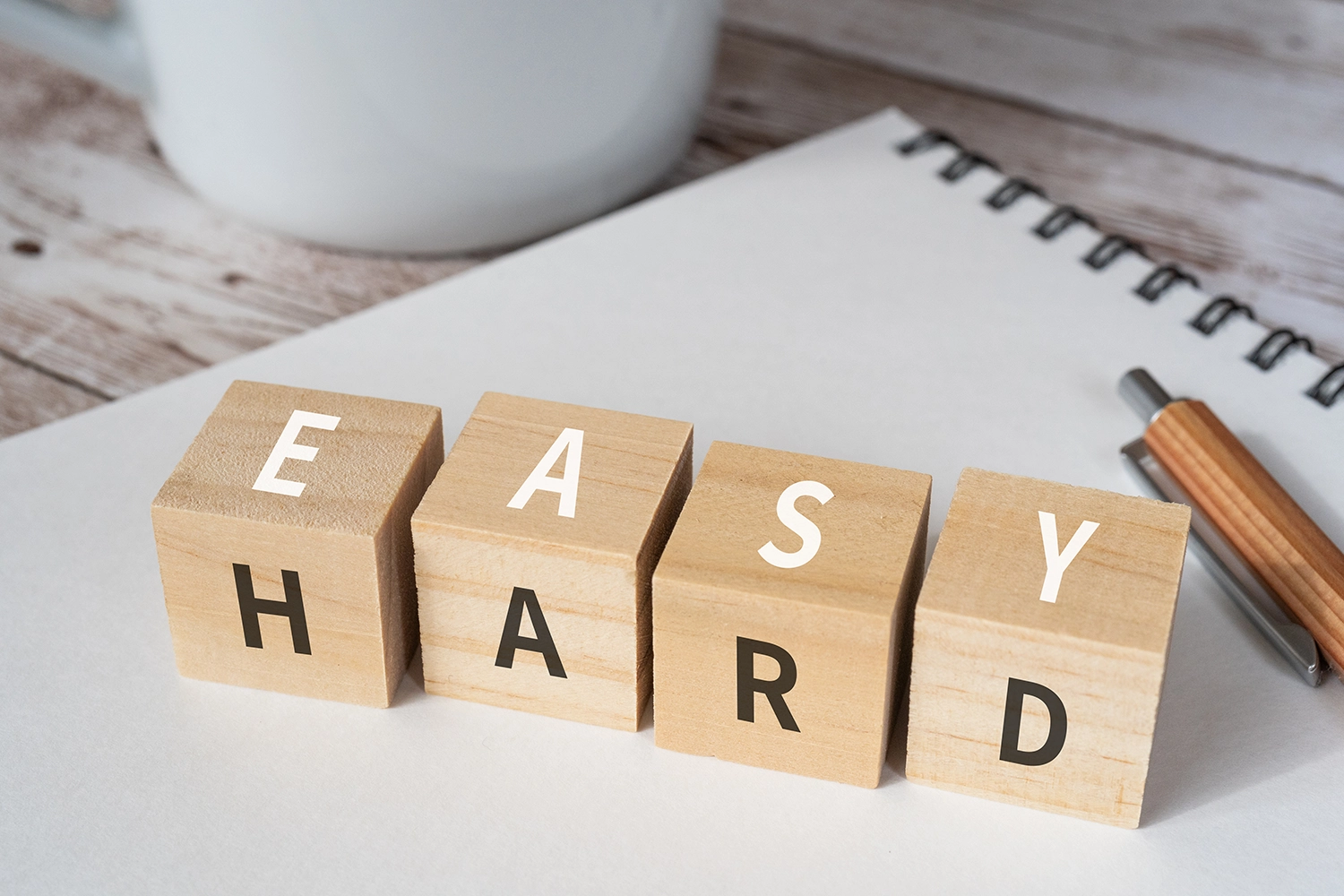 four wooden blocks showing letters for eas y and hard on different sides